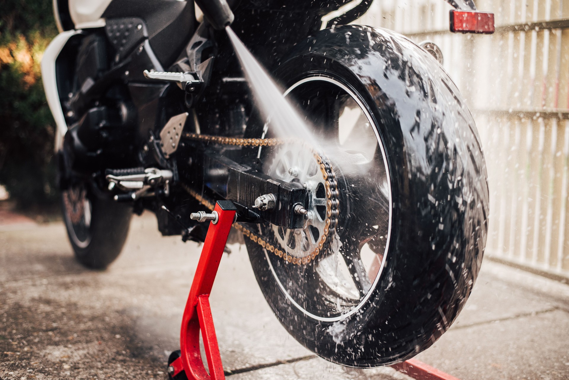 Washing motorcycle chain with high pressure jet, close-up.